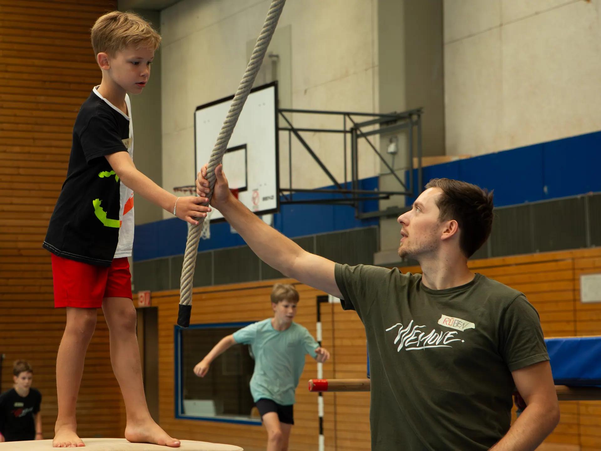 WEMOVE.-Trainer sichert einen Jungen am Kletterseil in der Halle