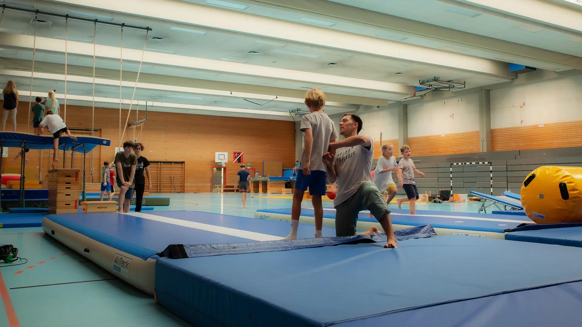 Trainer:in betreut Kinder beim WEMOVE.-Ferienprogramm in der Halle in Freiburg