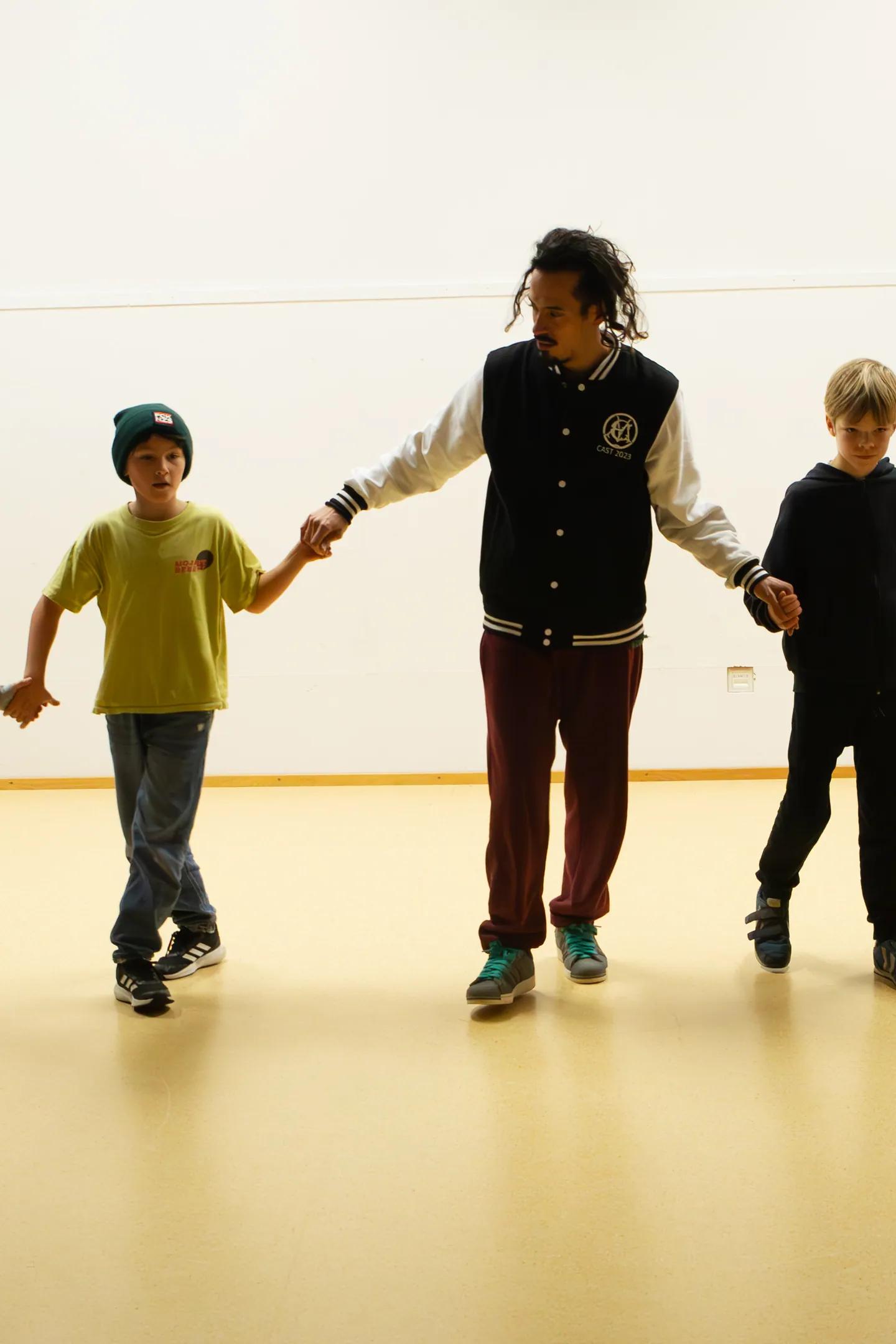 Trainer geht Hand in Hand mit einer Kindergruppe durch die Halle